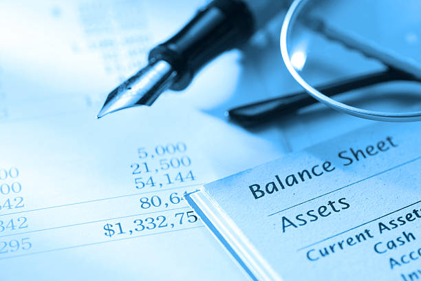 Close-up of a balance sheet showing financial figures, a fountain pen, and eyeglasses