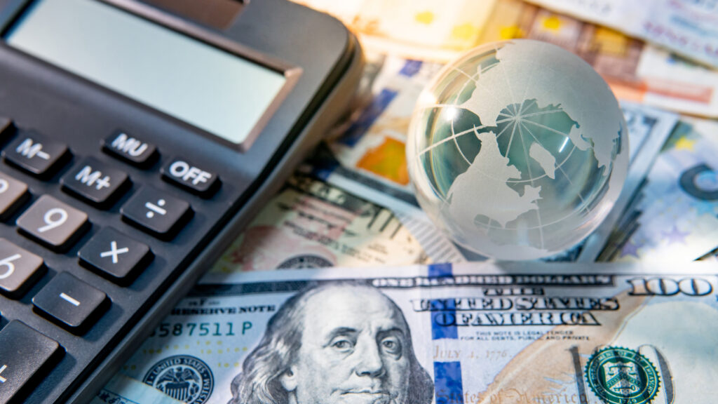 Calculator, globe, and international currency notes representing global financial and tax concepts.