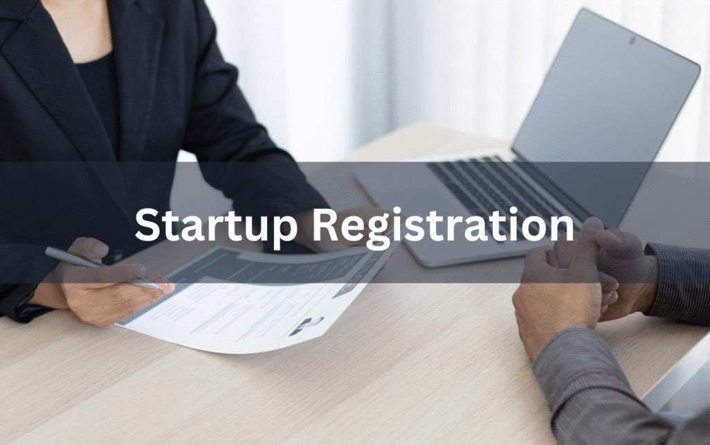 Two professionals discussing documents at a desk with a laptop, overlaid with the text “Startup Registration,” symbolizing new business incorporation and legal setup.