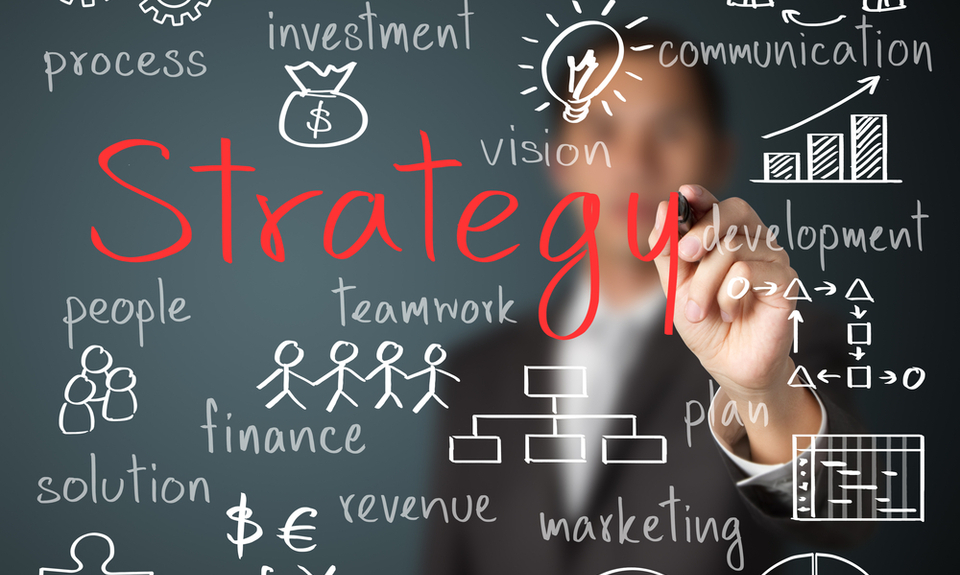 Business strategy concept with a person writing "Strategy" on a transparent board, surrounded by icons and keywords like finance, teamwork, and vision.