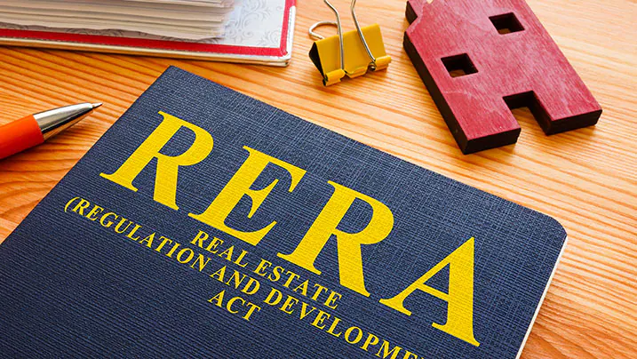 RERA (Real Estate Regulation and Development Act) booklet on a wooden desk with pen and house model
